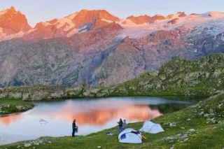 Two tents and three people set up for the night in the mountain